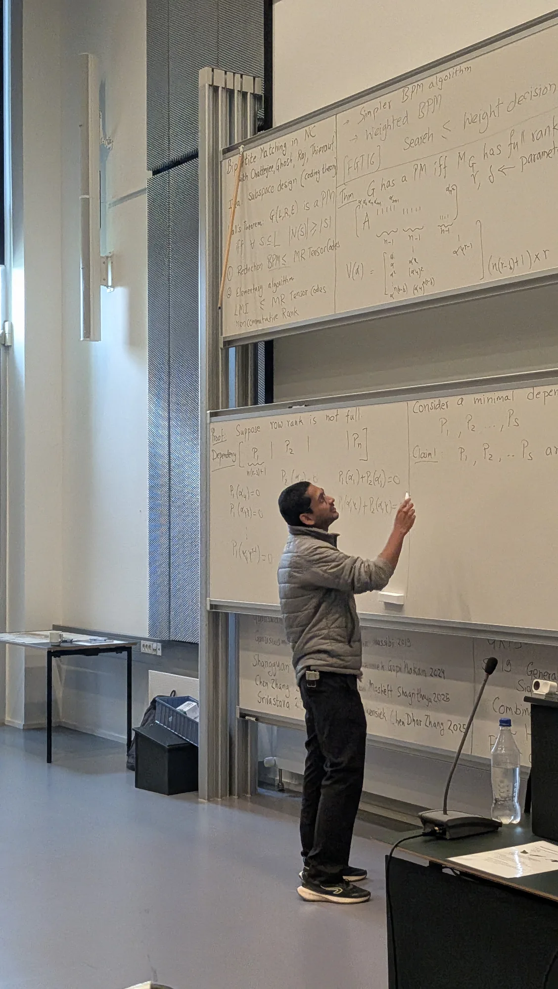 Rohit Gurjar presenting the bipartite matching proof, with the board-moving hook stuck on the upper board.